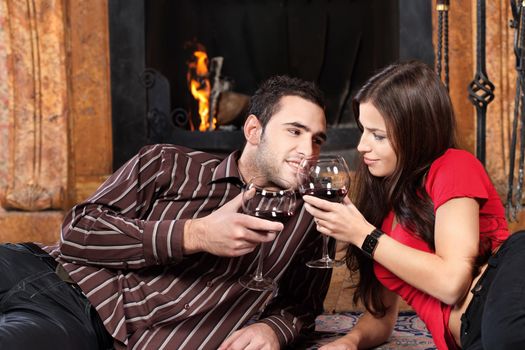 Young couple near fireplace holding glass of wine