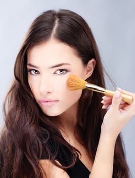 Portrait of a pretty young woman holding powder brush