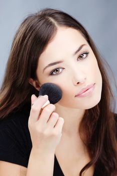 woman doing makeup with powder brush