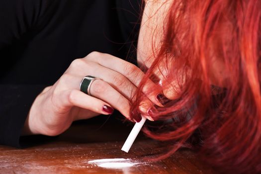 Young depressed woman snorting narcotics