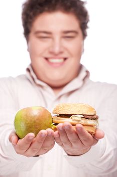 apple and hamburger in hands of a young chubby man, isolated on white