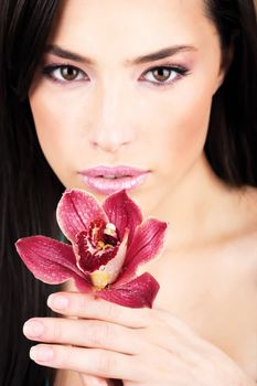 Red orchid in hands of a pretty woman, focus on flower