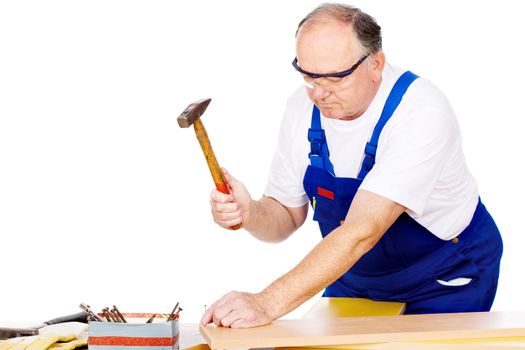 Middle age worker knocking the nail in board, isolated on white background