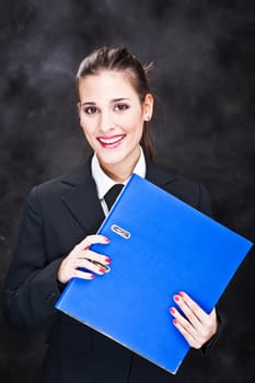 Young smiled business woman with files on dark background