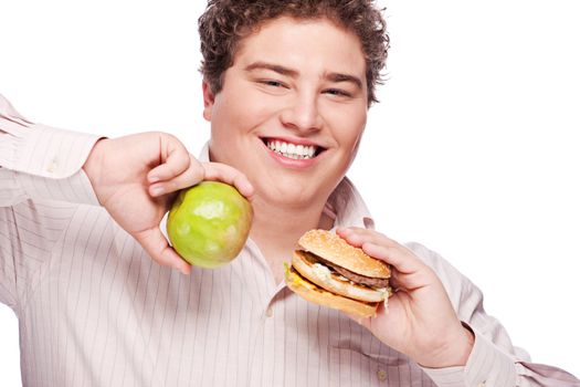 Young chubby man holding apple and hamburger, isolated on white