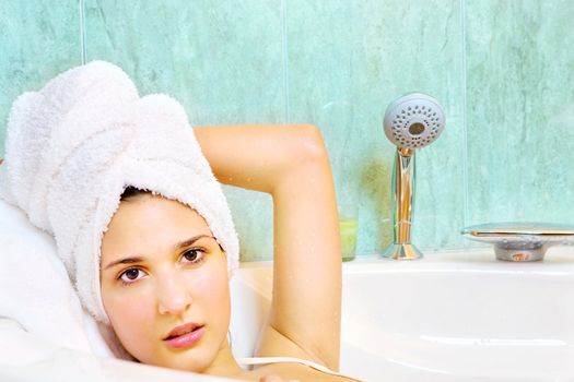 Young woman with white towel on head in the bathtub
