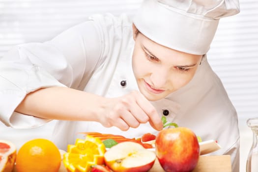 pretty young chef decorating delicious fruit plate