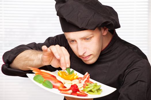 chef in black uniform decorating delicious fruit plate