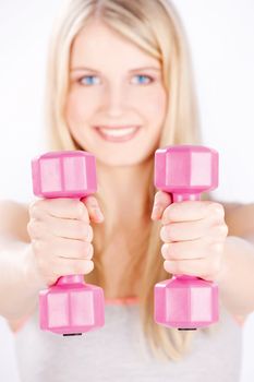 Young woman with two weights doing fitness exercises, focus on weights