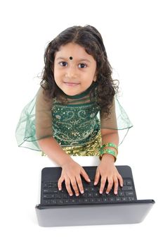 Little Indian girl using a laptop on table, isolated on white background