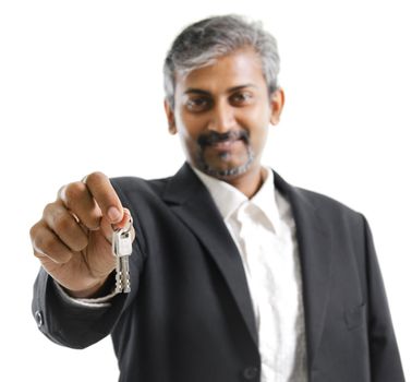 Mature adult Asian Indian man arm out holding a new key over white background