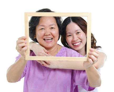 Mixed race Asian senior mother and adult daughter looking fun through an empty frame