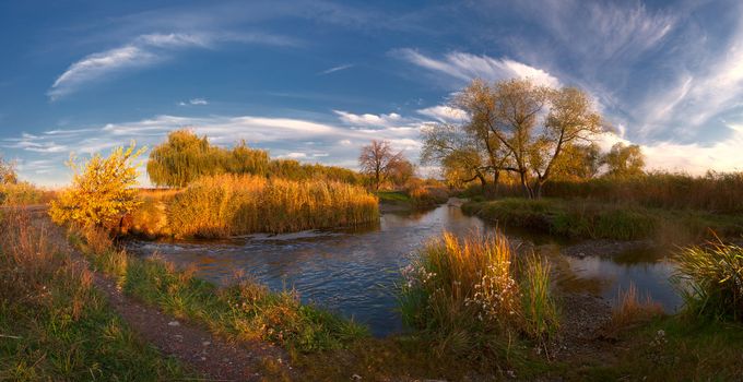 Colorful autumn landscape on evening river with majestic clouds. Panorama