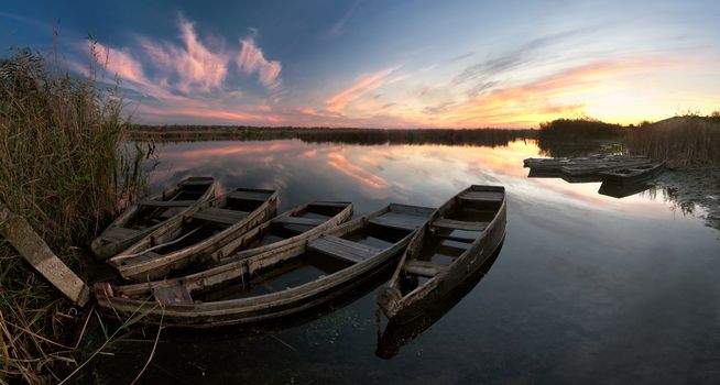 Evening colorful landscape with boats on the river and majestic sky reflection in the water