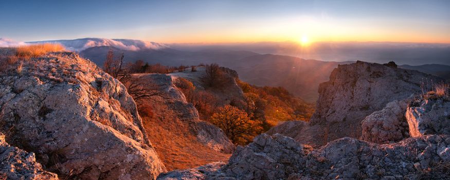 Sunrise panorama in the mountain, first sun rays through clouds