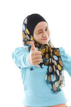 Cute young Muslim girl giving a thumb up sign over white background