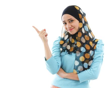 Cute young Muslim woman pointing on empty space, isolated on white