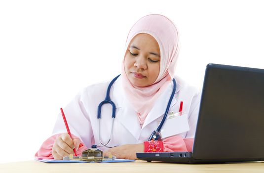 Muslim female doctor writing report on her working desk