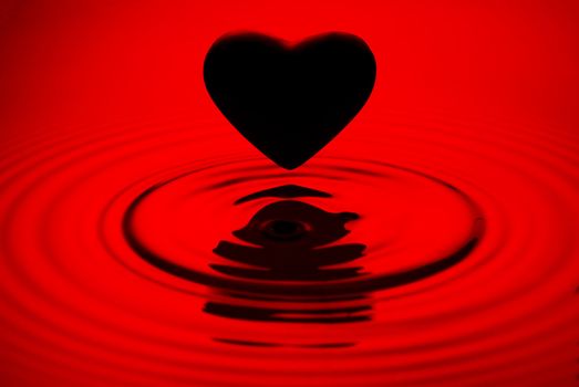 Black heart siluett over red water ripples background