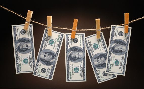 US Dollars Hanging on Rope with Clothespins on dark background