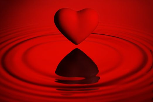 Red heart over red water ripples background
