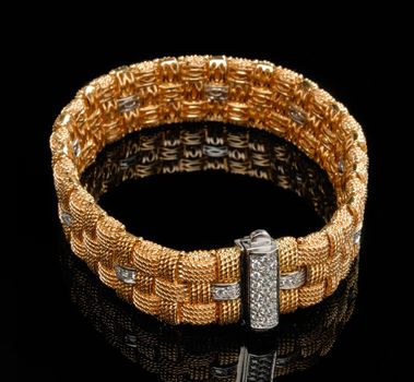 Golden bracelet with diamonds over black background