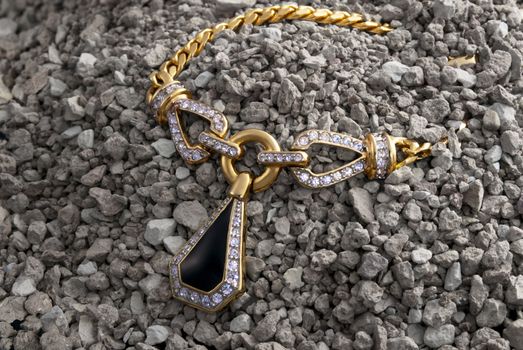 Gold necklace with pendent and diamonds in the pile of pebbles