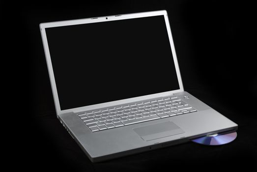 Silver portable computer with CD inserted. 3/4 view.