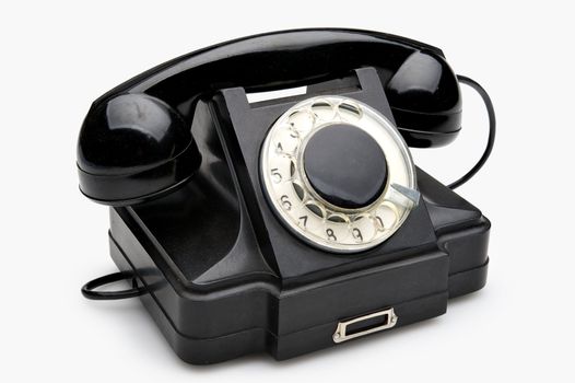 Old black vintage rotary style telephone isolated over a white background