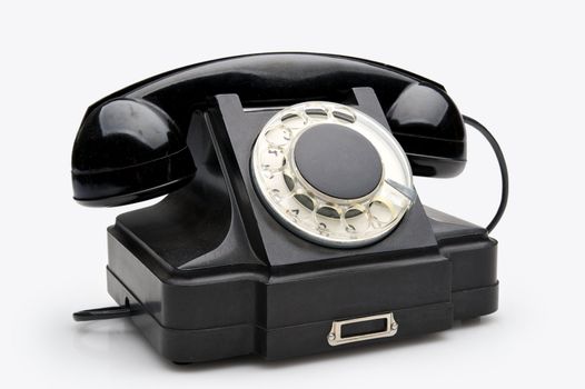 Old black vintage rotary style telephone isolated over a white background