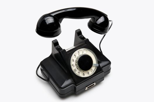 Old black vintage rotary style telephone isolated over a white background