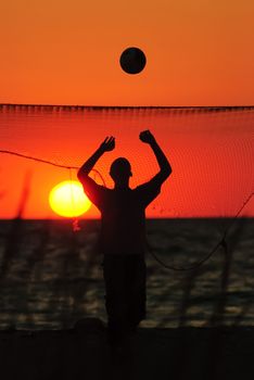 Family playing beach volleyball in the sunset