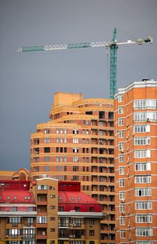 Architectural abstract of modern multi apartments building and hoisting crane in a sunset (recent development)