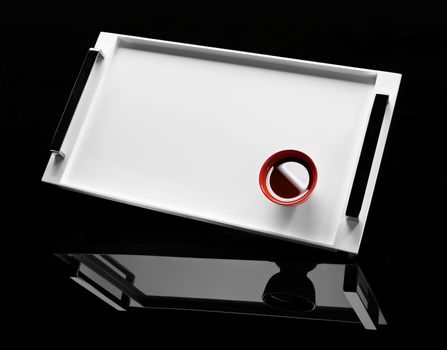 Red cup of tea on a white tray with mirror. Black background