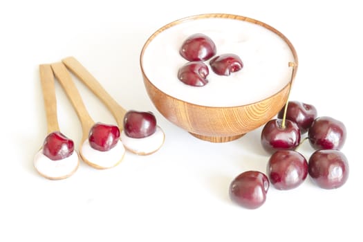 Top view of a bowl with cherries yoghurt,  wooden spoon with cherries and yogurt.