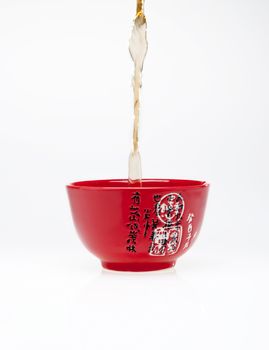 Pouring tea into chinese red teacup