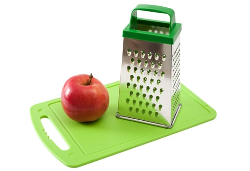 Apple and grater on a  green cutting board. 

