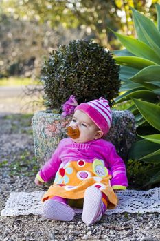 View of a newborn baby with pink suit next to a plant.
