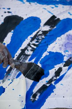 Detail of a hand with a paintbrush painting a colorful cloth.