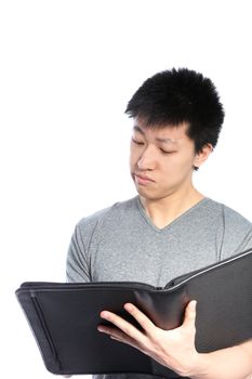 A casual young Asian man looking inside a binder isolated on white