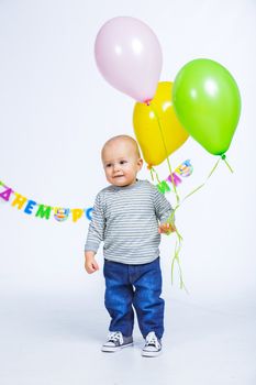 Cute funny little boy in first birthday with colored balloons. In the studio