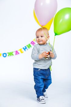 Cute funny little boy in first birthday with colored balloons. In the studio