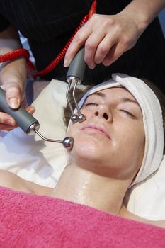 woman having a stimulating facial treatment from a therapist