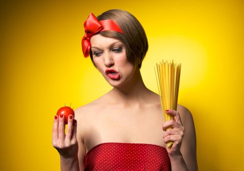 Portrait of young housewife holding potato and pasta in her hands. Retro styled. Isolated on yellow background