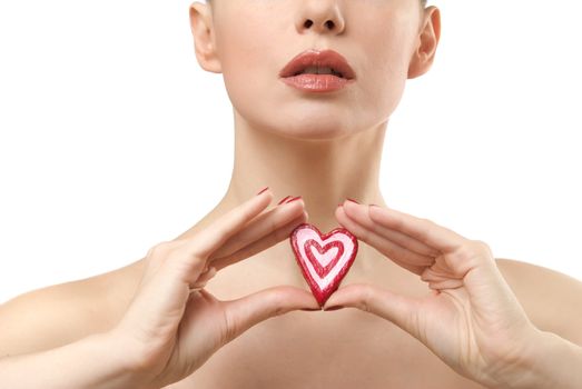 Young woman showing heart shaped candy. Lips closeup. Isolated on white background