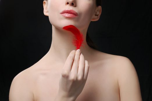 Young beautiful woman topless holding a plume