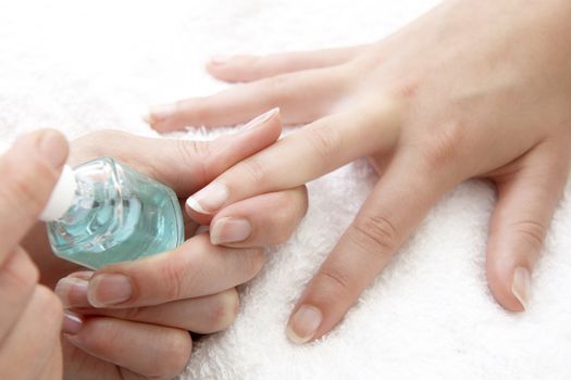 womans finger nails having clear varnish applied on white towel