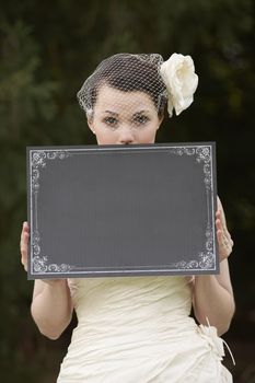 Pretty bride in wedding dress holding a blank board with space for copy