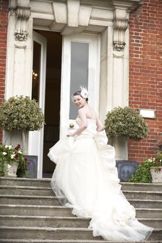 Pretty bride walking up steps in her wedding dress and smiling at camera