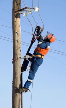 Electrician in blue overalls working at height